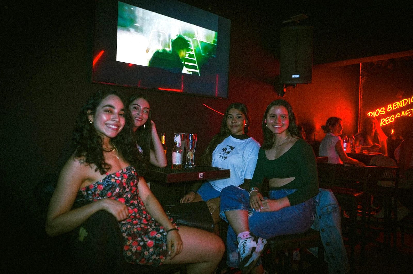 Amigas en una mesa frente a la pantalla de karaoke en A Kantar